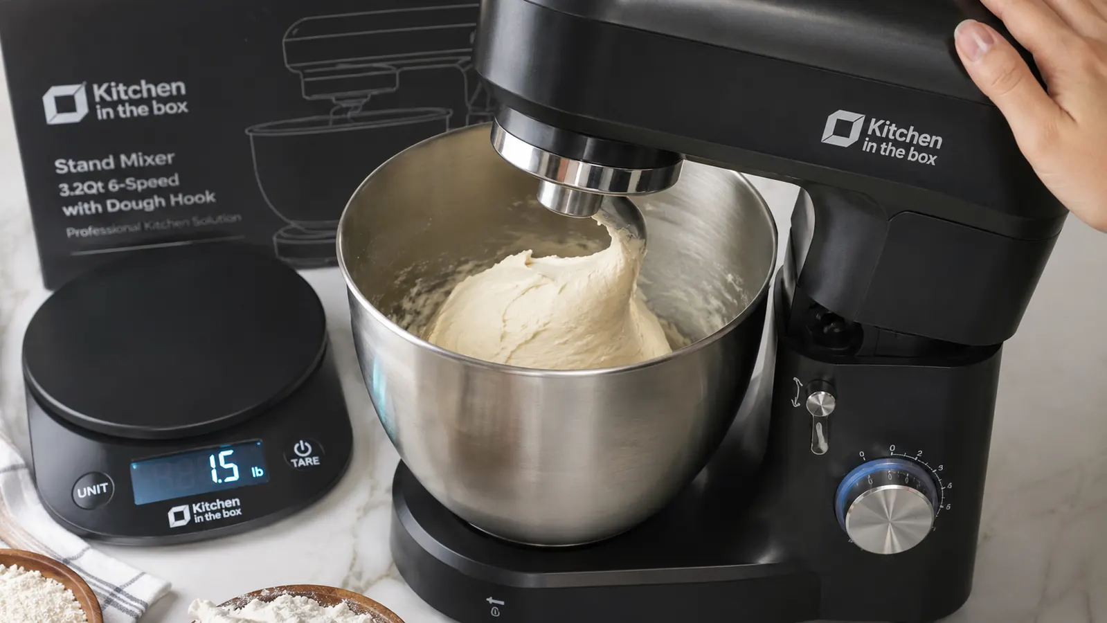 Hand holding a kitchen scale showing 1.5 pounds of stiff bread dough next to the Kitchen in the Box mixer's tilted head