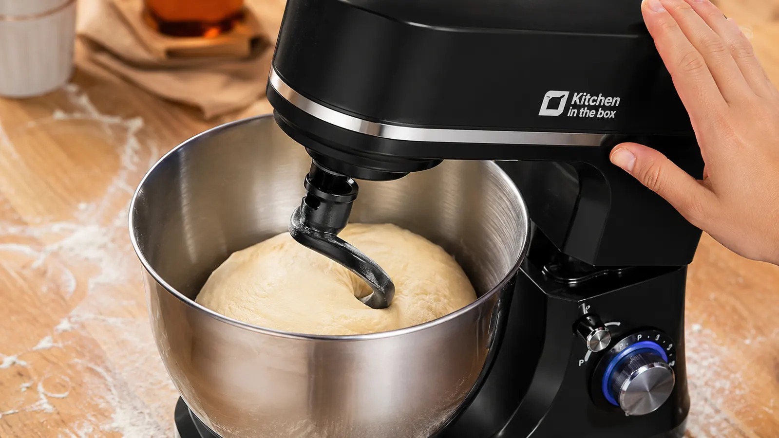 Dough hook kneading bread dough in the stainless bowl of a compact stand mixer