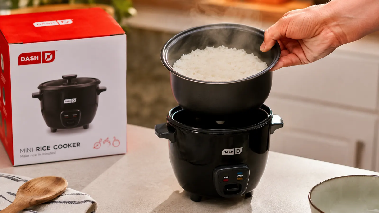 Hand lifting a removable ceramic nonstick pot out of a small black rice cooker after cooking