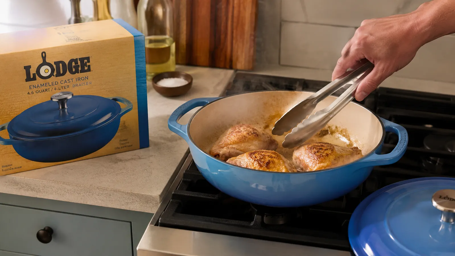 Hand searing chicken thighs skin side down in the Lodge Essential Enamel Braiser on a stovetop