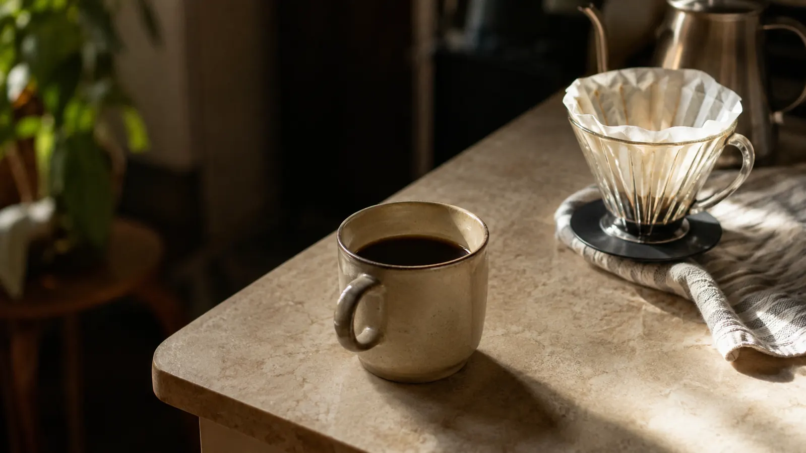A finished cup of pour-over coffee on a small kitchen counter in early morning light